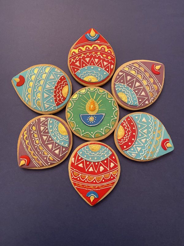 Hand-decorated Diwali diya sugar cookies arranged in a rangoli flower